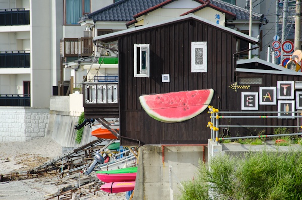 <b>海沿いの道を歩いているとヘンテコリンな建物を見つけた。「へんな建物は何?」って後できいたらココは個人所有の地元の仲間が集まる場所らしく、これもブルースさんが作ったスイカのオブジェだった(笑)。神社にある橋を越えたらオアシスへ到着。現場にはブルースさんの仲間のカメラマンが集まっていた。右写真:左側はミュージシャンを数多く撮っている仁礼博さん、ブルースの右側は日本に於けるサーフィン写真界の第一人者、横山泰介さん。地元の不良オヤジではなくて(失礼!笑)、個性的なおじさんたちだが、そのうちココで登場して頂きたいくらい有名な写真家の先輩たちだ</b>